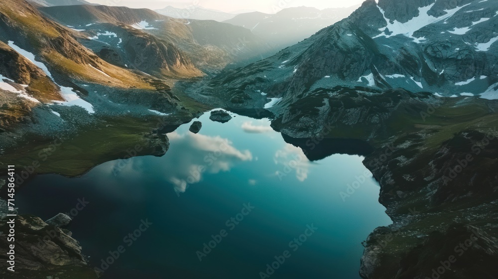 Obraz premium an aerial view of a mountain lake with snow on the mountains in the foreground and a blue body of water in the middle of the lake in the foreground.
