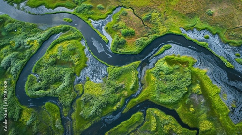  an aerial view of a river running through a lush green field next to a lush green field with trees and grass on both sides of the river's sides.