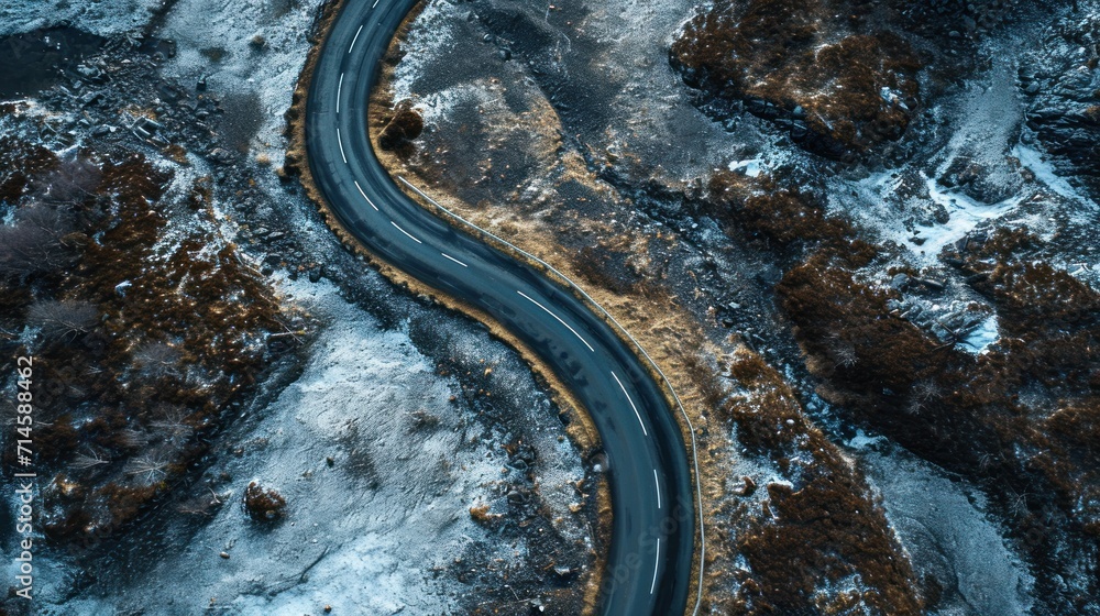  an aerial view of a curved road in the middle of a snow - covered area with trees and bushes on either side of the road is a snow - covered road.