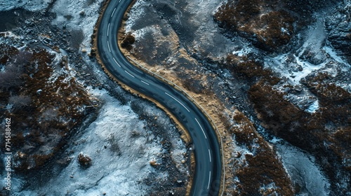  an aerial view of a curved road in the middle of a snow - covered area with trees and bushes on either side of the road is a snow - covered road.