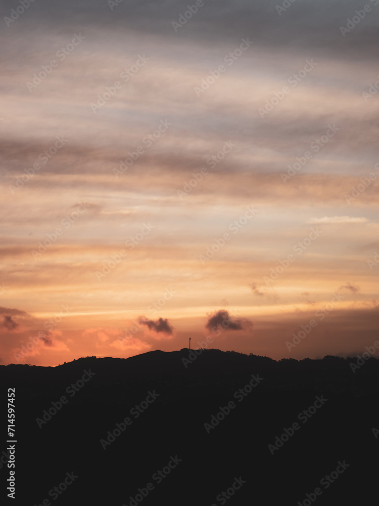 Silhoute of a windmill on top of a hill with golden hues