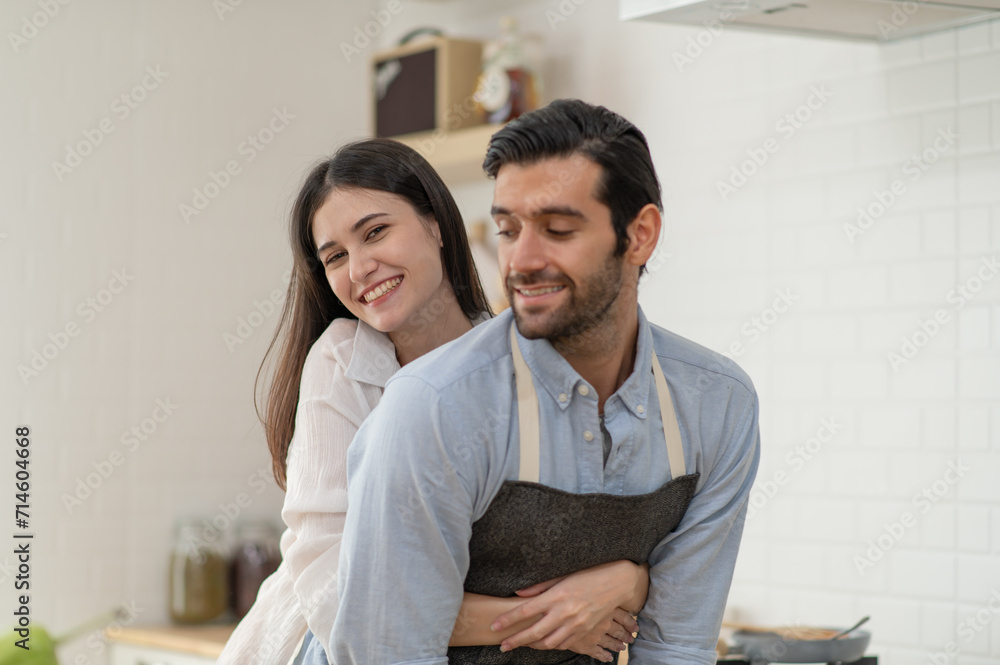 Obraz premium Happy couple in love cooking in the kitchen at home and hugging