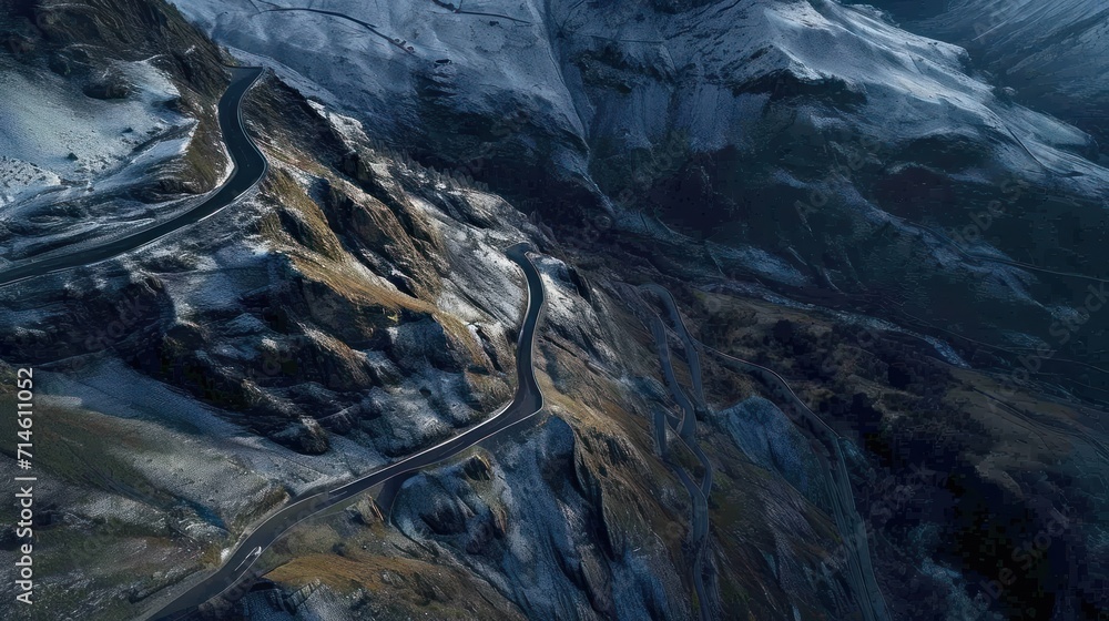  an aerial view of a mountain with a winding road in the foreground and a snow covered mountain in the background, taken from a bird's eye view.