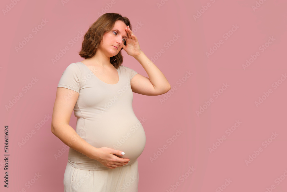 A sad pregnant woman on a pink studio background. Pregnancy in a unhappy woman with a belly, copy space A sad pregnant woman on a pink studio background. Pregnancy in a unhappy woman with a belly, copy space