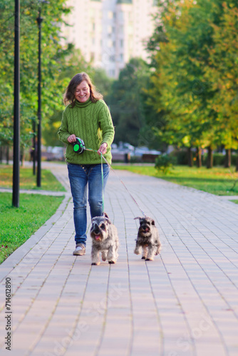 Happy adult woman walking with her dogs in the park. Selective focus.