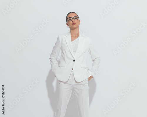 serious elegant bussinesswoman with glasses holding hands in pockets photo