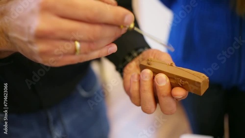 The man holds a block of clay and a stack and shows how to use it photo