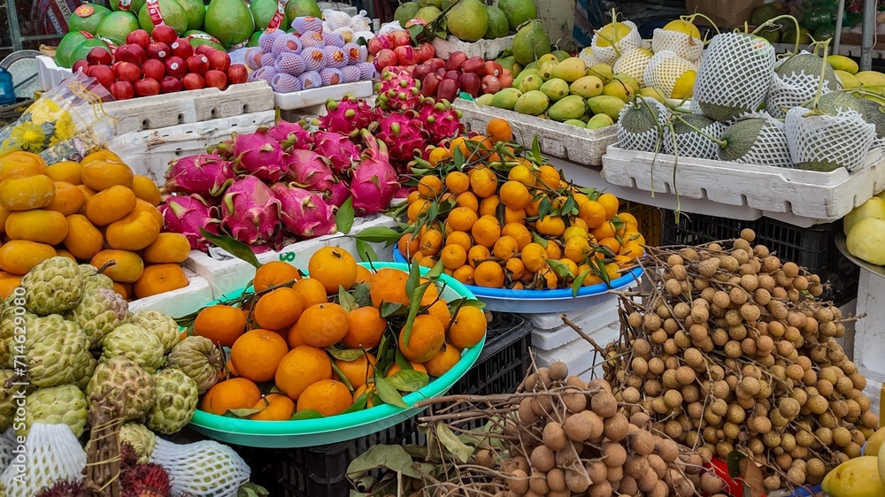 Colorful assortment of exotic fruits displayed at a tropical market, including dragon fruit, mangoes, and oranges