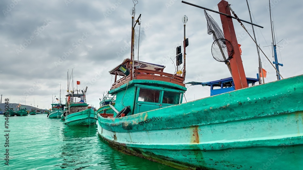 Colorful fishing boats moored in calm water under a cloudy sky, showcasing a traditional maritime setting