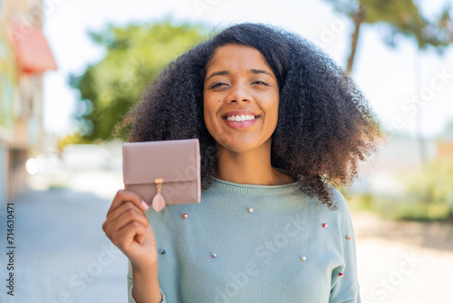 Young African American woman holding a wallet at outdoors with happy expression photo
