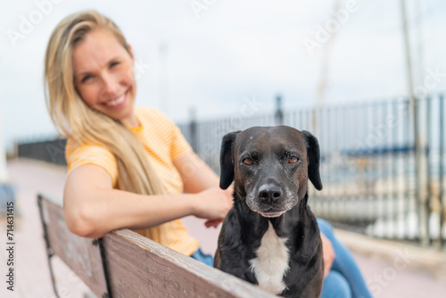 Young blonde woman with her adorable black dog at outdoors