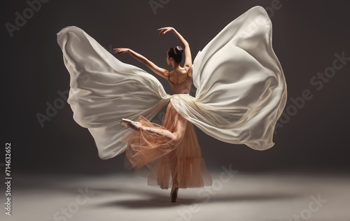 Ballerina. Young graceful woman ballet dancer, dressed in professional outfit, shoes and beige weightless skirt is demonstrating dancing skill. Beauty of classic ballet.