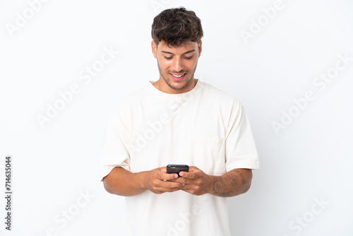 Young caucasian handsome man isolated on white background sending a message with the mobile © luismolinero