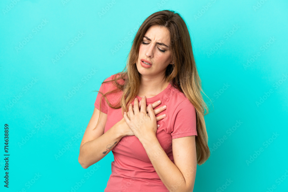 Young caucasian woman isolated on blue background having a pain in the heart Young caucasian woman isolated on blue background having a pain in the heart