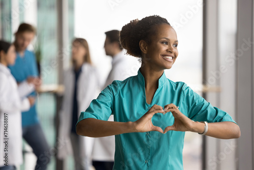 Fotografi Happy dreamy beautiful African doctor woman promoting cardio healthcare checkup,