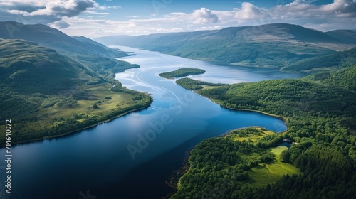  an aerial view of a body of water surrounded by lush green hills and a blue sky with puffy white clouds in the middle of the middle of the picture.