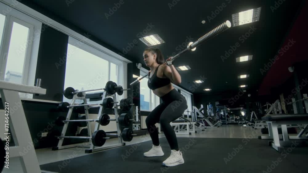 An athlete performs barbell squats with an empty bar in a brightly lit gym. Her steady pace and composed finish highlight balance, controlled posture, and lower body strength in training. An athlete performs barbell squats with an empty bar in a brightly lit gym. Her steady pace and composed finish highlight balance, controlled posture, and lower body strength in training.