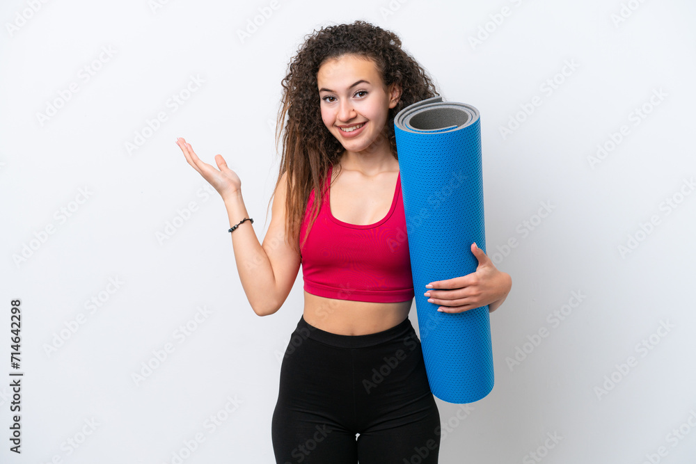 Young sport Arab woman going to yoga classes while holding a mat isolated on white background extending hands to the side for inviting to come
