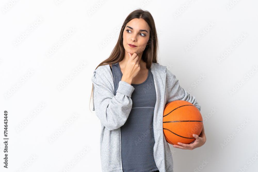 Young woman playing basketball isolated on white background looking to the side and smiling Young woman playing basketball isolated on white background looking to the side and smiling