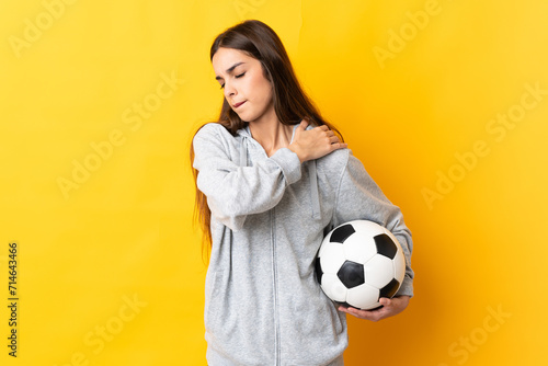 Young football player woman isolated on yellow background suffering from pain in shoulder for having made an effort © luismolinero