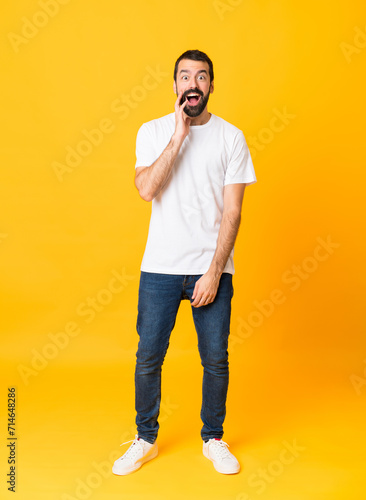 Full-length shot of man with beard over isolated yellow background with surprise and shocked facial expression