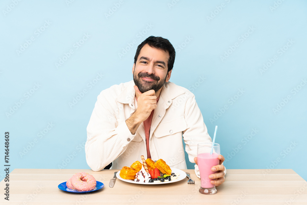 Man at a table having breakfast waffles and a milkshake Man at a table having breakfast waffles and a milkshake