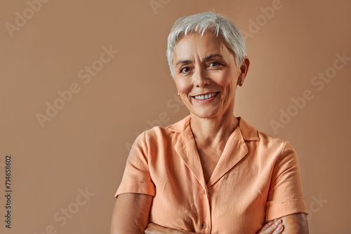 Woman's beauty and maturity. Portrait of a beautiful gray-haired woman with a short hairstyle on a beige background.