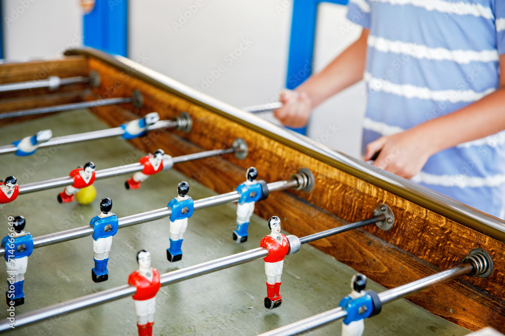 Close-up of kid boy playing table soccer. Happy excited child having fun with family game with siblings or friends. Positive kid.