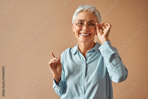 Beautiful retired woman holding glasses and looking at camera. Selection of eyeglass frames, vision test.