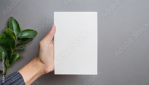 hand holding a5 template blank paper mockup on gray background photo