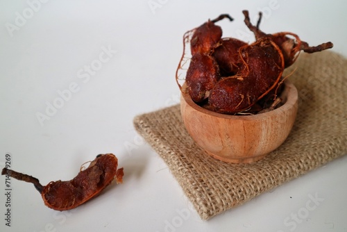 Asam Jawa or Tamarindus indica. Tamarind beans in a bowl on a white background, healthy fruit. Selective focus. photo