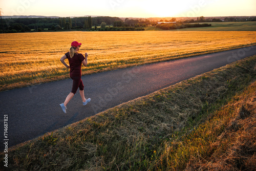 Road running. Woman runs during summer sunset outdoors. Fitness, jogging and sports activity