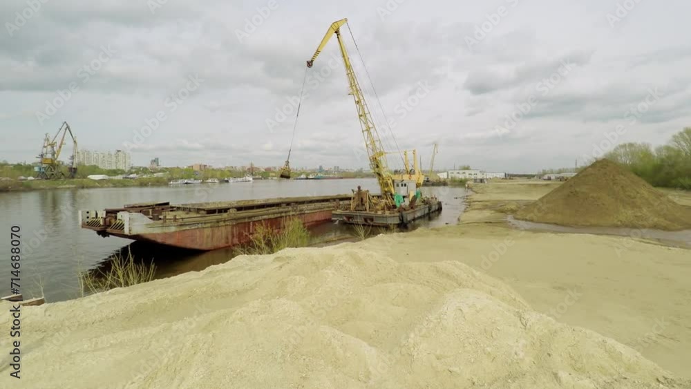 Crane unloads sand from cargo vessel to shore of Volga river Crane unloads sand from cargo vessel to shore of Volga river