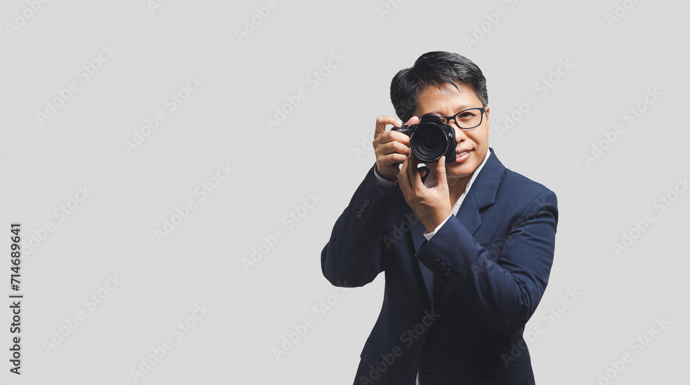 Woman photographer with black short hair is taking a photo while standing on a gray background. Woman photographer with black short hair is taking a photo while standing on a gray background.