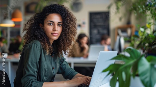 Beautiful Middle Eastern Manager Sitting at a Desk in Creative Office in the Evening. Young Stylish Female Using Laptop Computer in Marketing Agency, Developing Projects and Schedules