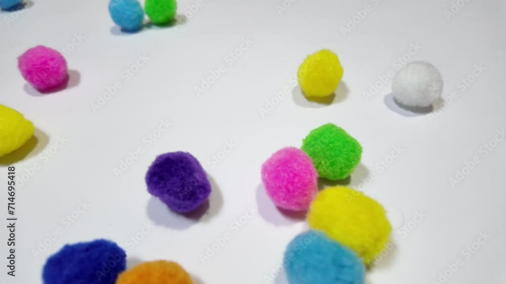 Colorful pom poms are sliding from right to left on a white background. Colorful pom poms are sliding from right to left on a white background.