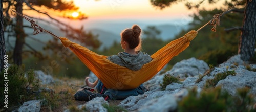 Young woman relaxing in hammock on top of the mountain at sunrise photo