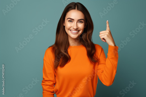 Young woman giving thumbs up gesture on a bright blue background. Woman on the blue background is holding a thumbs up as a sign of approval.