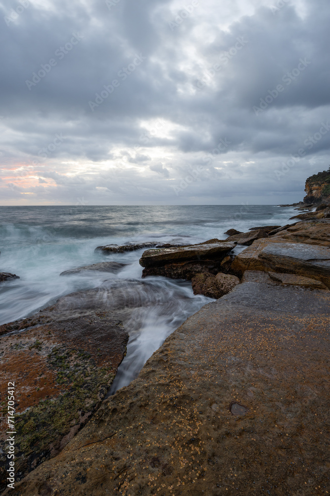 Cloudy sunrise view over a rocky coastline.