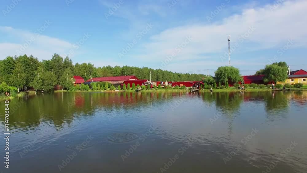 Small lake with reflection of fish farm buildings on shore Small lake with reflection of fish farm buildings on shore