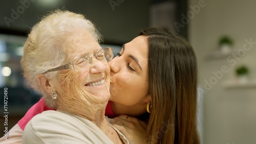 Granddaughter kissing her grandmother with lots of love photo