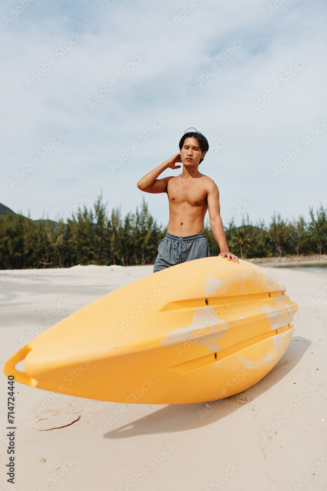 Obraz premium Happy Asian Man Kayaking on a Tropical Beach: Enjoying an Active Summer Vacation