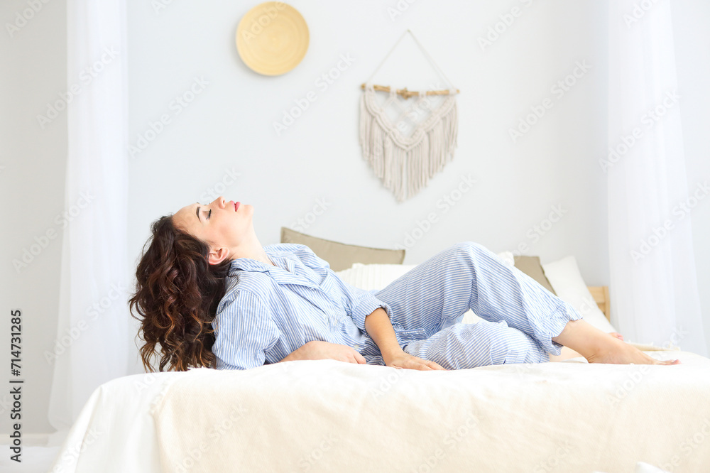 Brunette woman in pajamas resting on bed Brunette woman in pajamas resting on bed