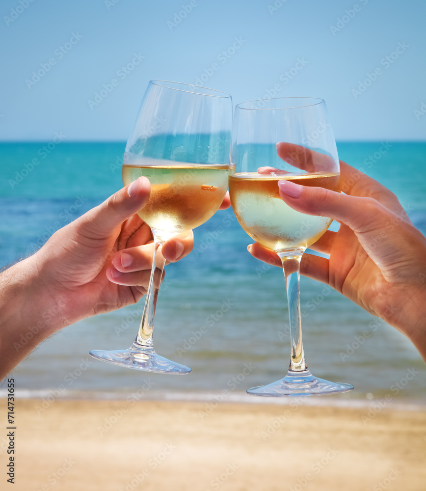 Man and woman clanging wine glasses with white wine at sea background
