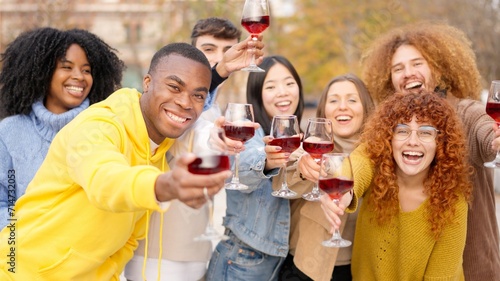 Multi-ethnic friends toasting with wine to the camera outdoors