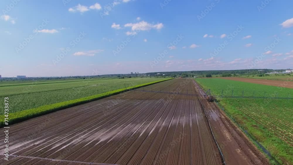 Tractor moves pouring system across farm field at summer sunny day. Aerial view Tractor moves pouring system across farm field at summer sunny day. Aerial view