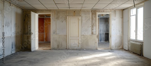 Inside a vacant office building, a room is seen with empty walls and open doors.