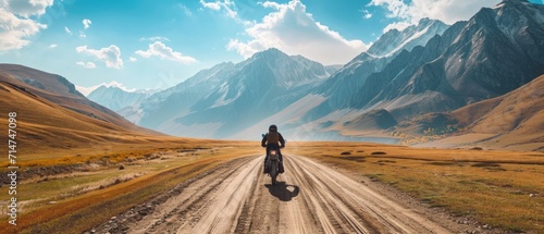 Aeriel view of a man riding a motorcycle bike on a mountainous valley road