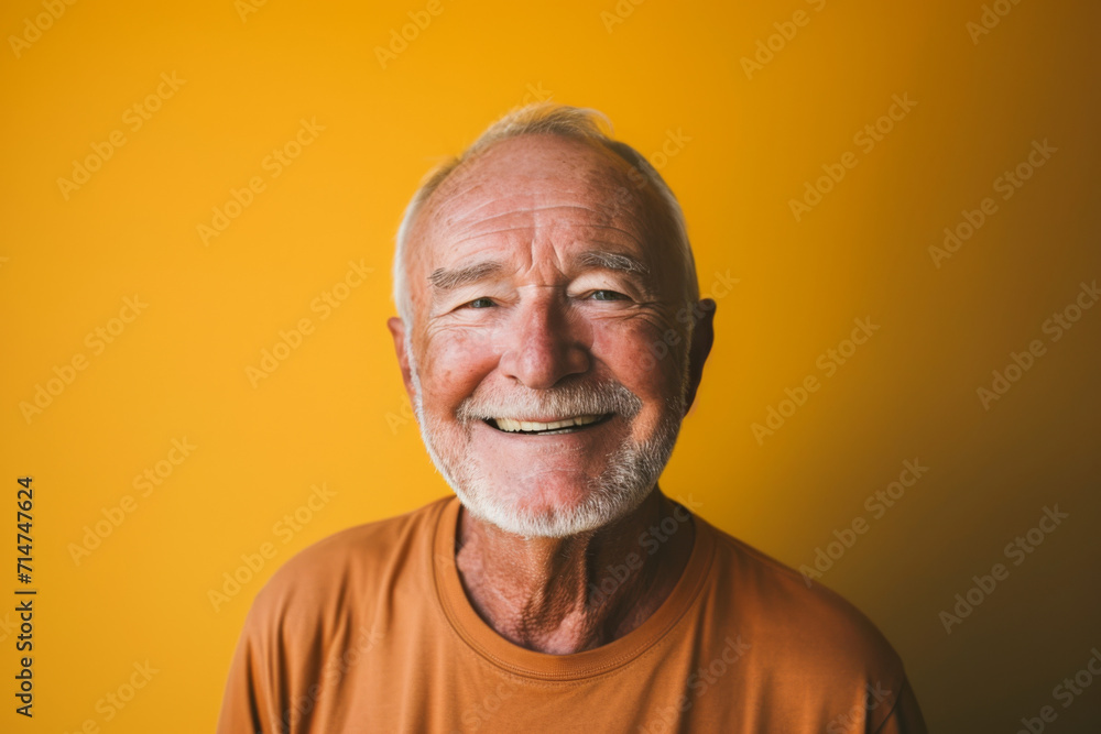 An older man with a beard is smiling in front of a yellow background An older man with a beard is smiling in front of a yellow background