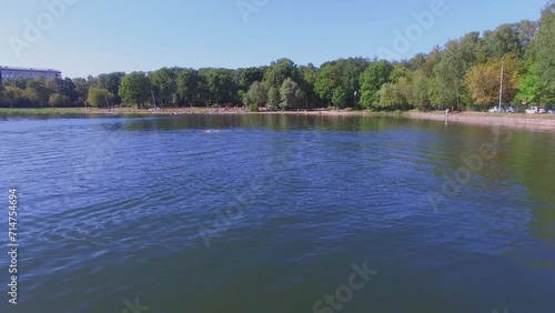 Toy boat moves by Putyaevsky pond in city park with people  photo